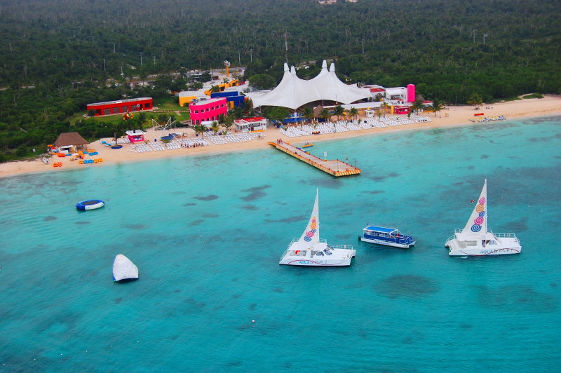 Aerial view of Playa Mia beach club in Cozumel with white tent pavilion, sandy beach and Aqua Dream catamarans on turquoise water