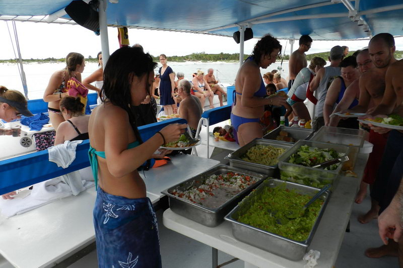 Pasajeros nadando y haciendo esnórquel frente al catamarán Raiatea en el turquesa Caribe Riviera Maya