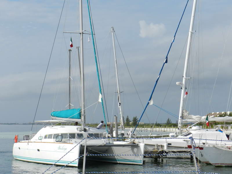 Catamarán Lagoon de 40 pies atracado entre veleros en la marina de Maroma cerca de Playa del Carmen, con la bandera mexicana sobre la Riviera Maya turquesa