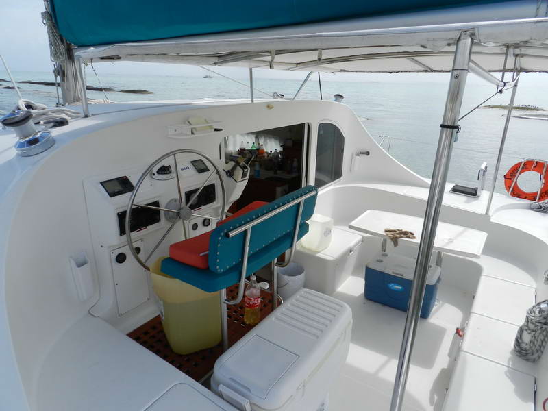 Timón abierto y cabina sombreada del catamarán Lagoon de Maroma con hieleras y bebidas frías, listo para un paseo de día en Playa del Carmen