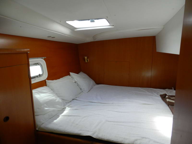 Camarote doble interior con paneles de madera cálida y ropa de cama blanca a bordo del catamarán Lagoon, ideal para descansar a la sombra en la Riviera Maya