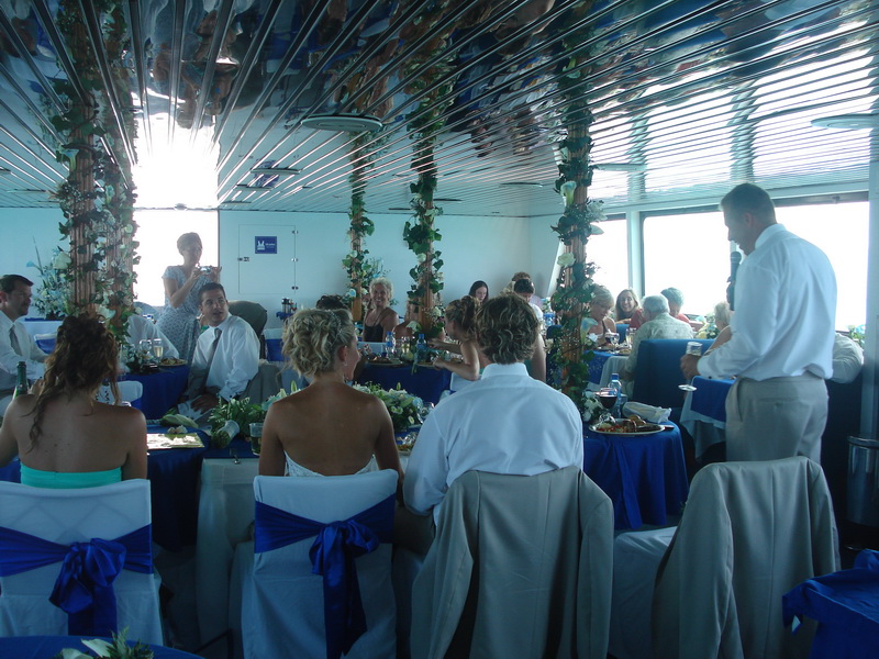 Mesas de recepción de boda elegantemente decoradas con manteles azul y blanco a bordo del barco Discovery en Cancún