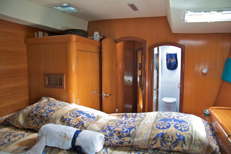 Camarote doble con aire acondicionado, paneles de madera cálida, ropa de cama con estampado y baño privado a bordo del catamarán Lagoon 470 en Puerto Morelos