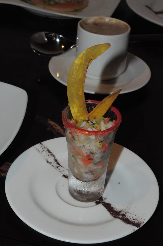 Ceviche de mariscos servido en un vaso alto helado con totopos crujientes, presentado como canapé en un evento de playa en Maroma